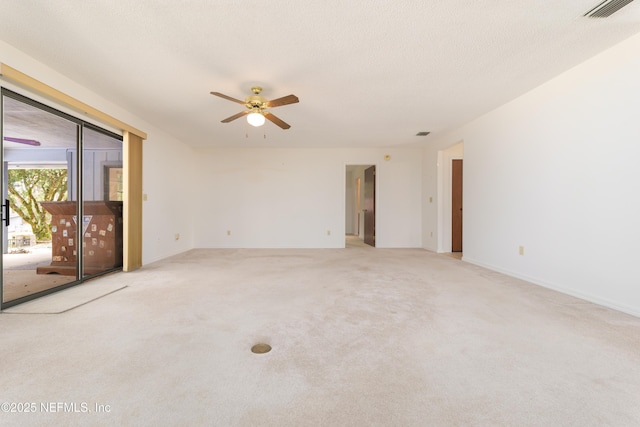 spare room featuring visible vents, light carpet, a textured ceiling, baseboards, and ceiling fan