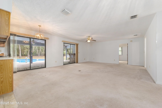 interior space with visible vents, light carpet, a textured ceiling, and ceiling fan with notable chandelier