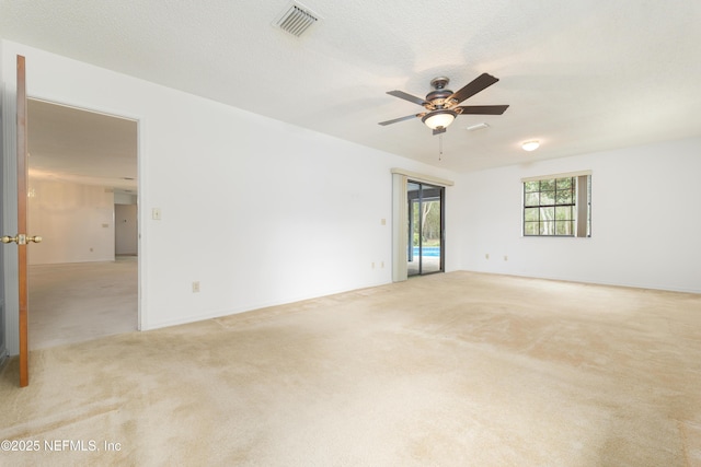 unfurnished room with light colored carpet, visible vents, and a textured ceiling