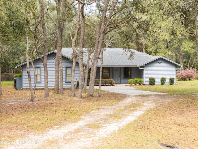 view of front of home with a front yard, driveway, and a shingled roof