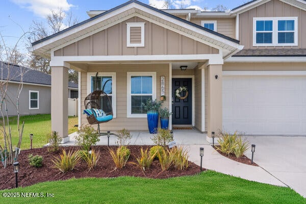 view of front of property featuring a porch, board and batten siding, concrete driveway, and a front yard