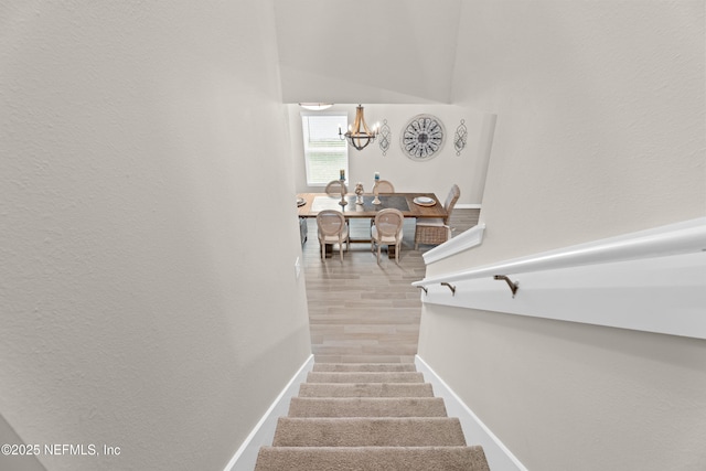 stairs featuring an inviting chandelier, wood finished floors, and baseboards