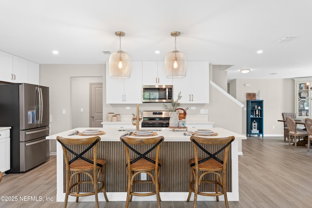 kitchen featuring a breakfast bar, light wood-style flooring, stainless steel appliances, and light countertops