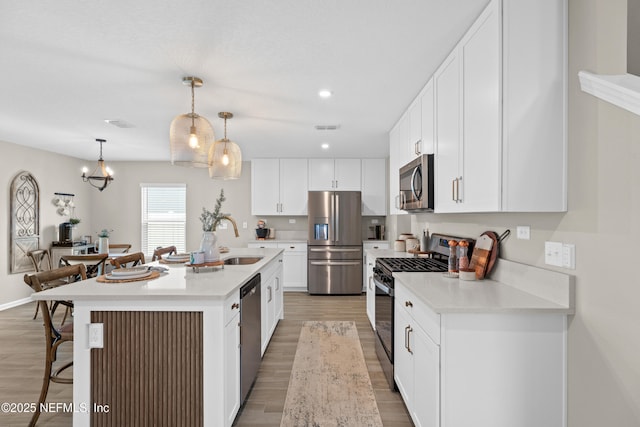 kitchen with visible vents, a breakfast bar, light wood-style flooring, a sink, and appliances with stainless steel finishes