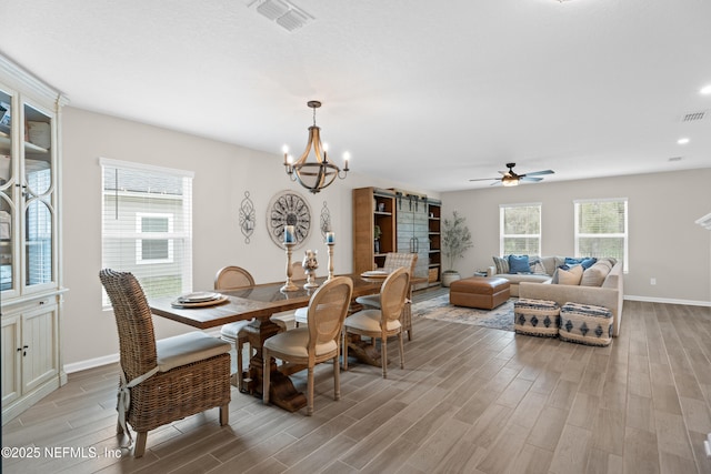 dining space with plenty of natural light, visible vents, light wood-type flooring, and a barn door