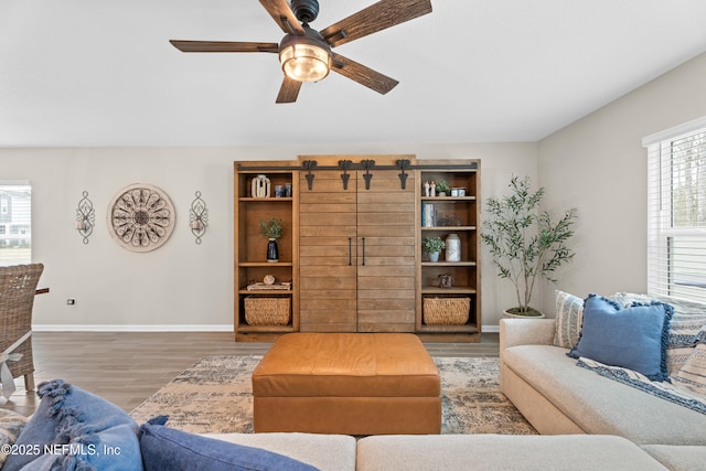 living area featuring baseboards, wood finished floors, and a ceiling fan