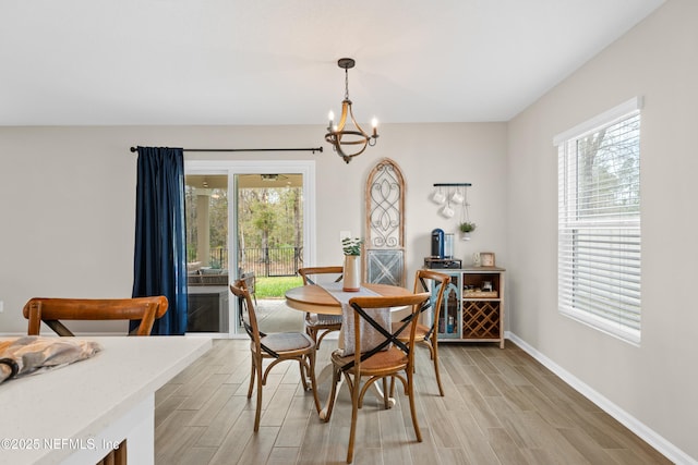 dining room featuring baseboards, light wood-style floors, and an inviting chandelier