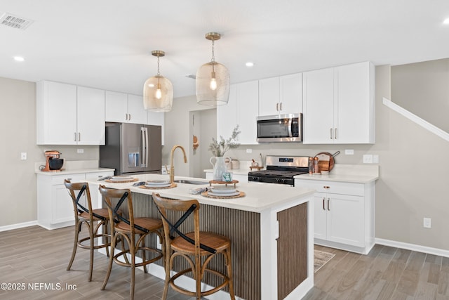 kitchen with visible vents, light wood-type flooring, light countertops, appliances with stainless steel finishes, and a sink