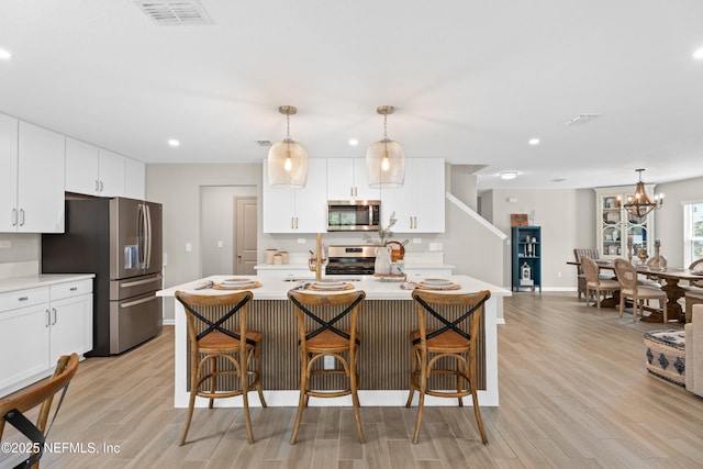 kitchen with light wood finished floors, visible vents, stainless steel appliances, and light countertops