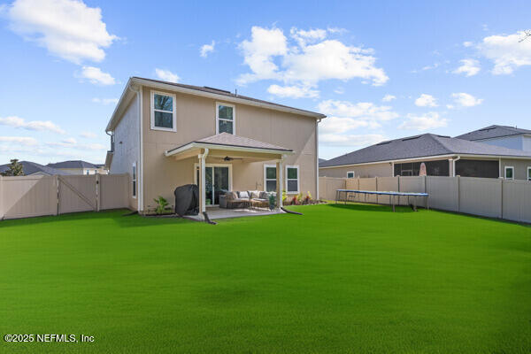 rear view of property with an outdoor living space, a trampoline, a fenced backyard, a patio, and a gate