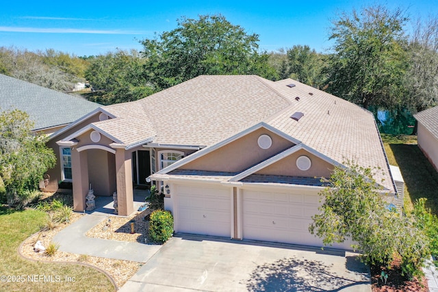 view of front of home with a garage, a shingled roof, driveway, and stucco siding