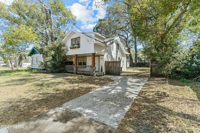 view of front of property featuring a porch, a front lawn, and fence