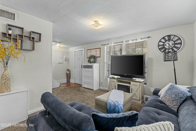 carpeted living area featuring baseboards, visible vents, a textured ceiling, and a textured wall