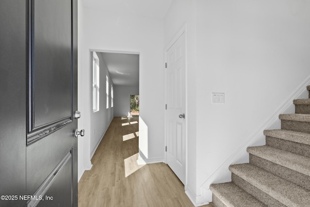 foyer entrance with baseboards, light wood-style floors, and stairs