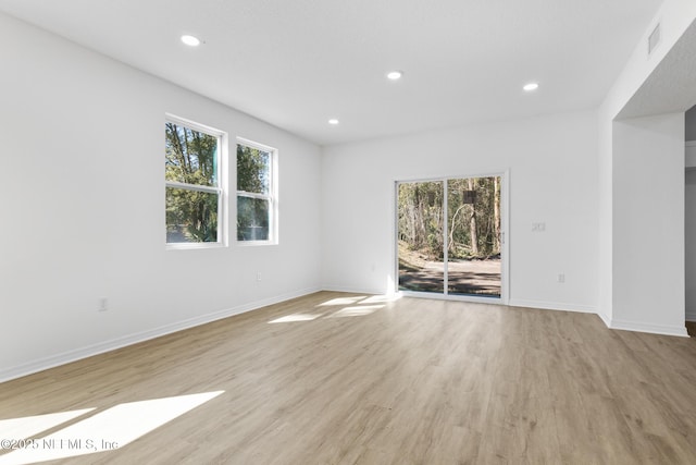 empty room with a wealth of natural light, baseboards, light wood-style floors, and recessed lighting