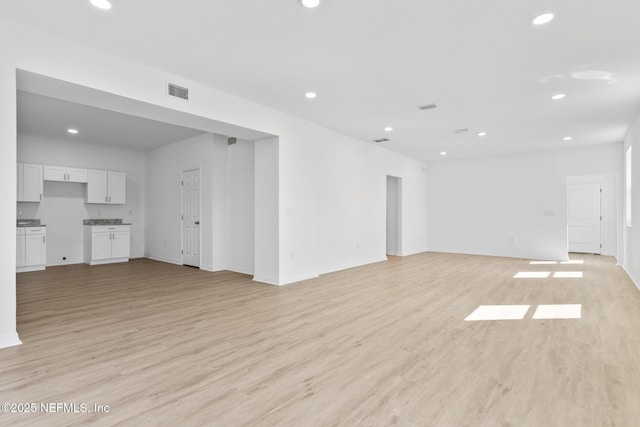 unfurnished living room with visible vents, recessed lighting, light wood-type flooring, and baseboards