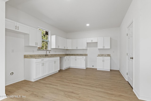 kitchen featuring white cabinets, light wood-style floors, and baseboards