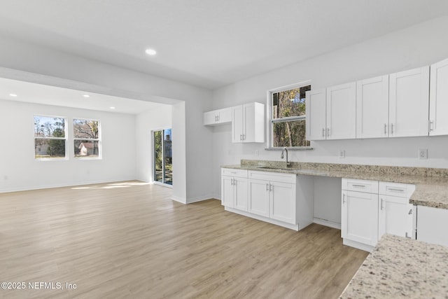 kitchen with white cabinetry, plenty of natural light, light wood-type flooring, and a sink