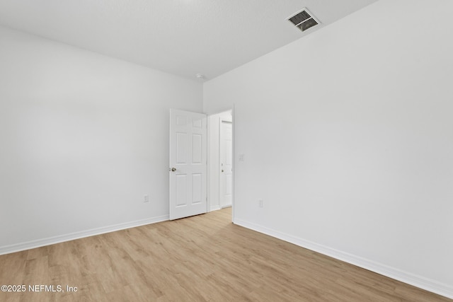 spare room featuring visible vents, baseboards, and light wood-style floors