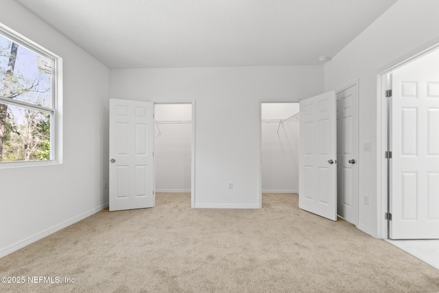 unfurnished bedroom with baseboards, carpet floors, and a spacious closet