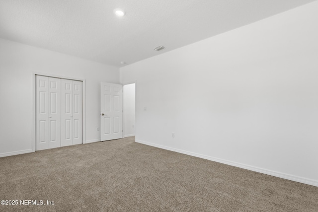 unfurnished bedroom featuring a closet, carpet floors, baseboards, and visible vents