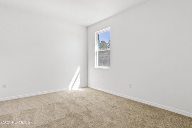 empty room featuring baseboards and light colored carpet