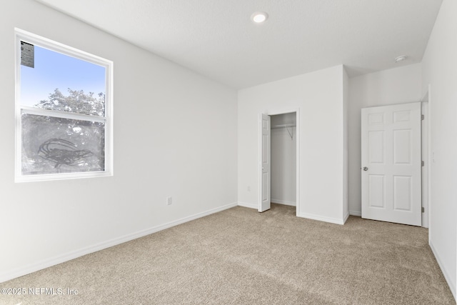 unfurnished bedroom featuring baseboards, carpet floors, and a closet