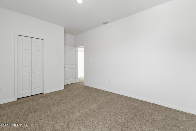 unfurnished bedroom featuring carpet flooring, baseboards, visible vents, and a closet