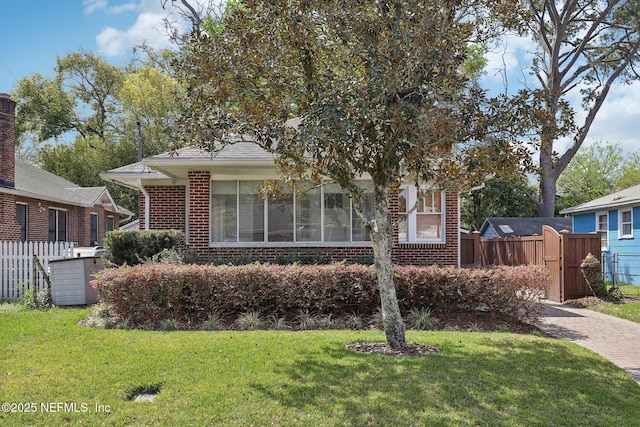 view of front of house featuring a front lawn, fence, and brick siding