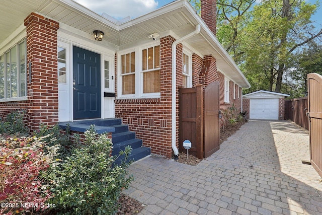 property entrance featuring brick siding, driveway, a chimney, and a garage