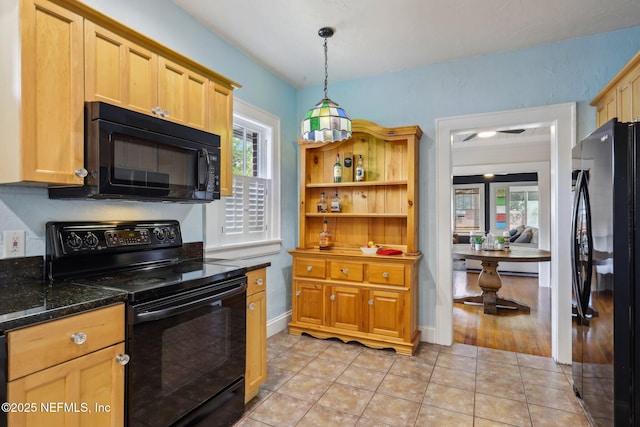 kitchen with light tile patterned floors, dark stone counters, black appliances, and pendant lighting