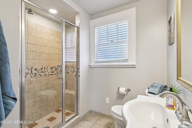 full bathroom featuring tile patterned flooring, a shower stall, toilet, and a sink