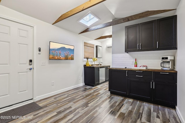 kitchen with lofted ceiling with skylight, tasteful backsplash, baseboards, and wood finished floors