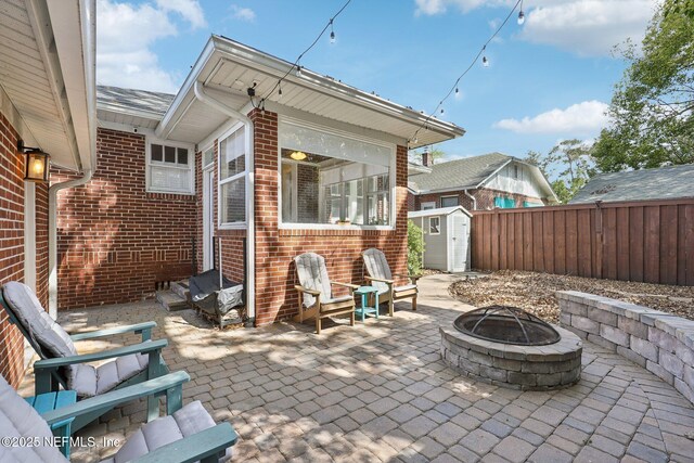 view of patio / terrace featuring an outbuilding, a storage shed, a fire pit, and fence