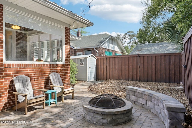 view of patio / terrace featuring an outbuilding, a fenced backyard, a shed, and an outdoor fire pit