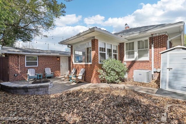back of property featuring brick siding, central AC unit, an outbuilding, and a patio