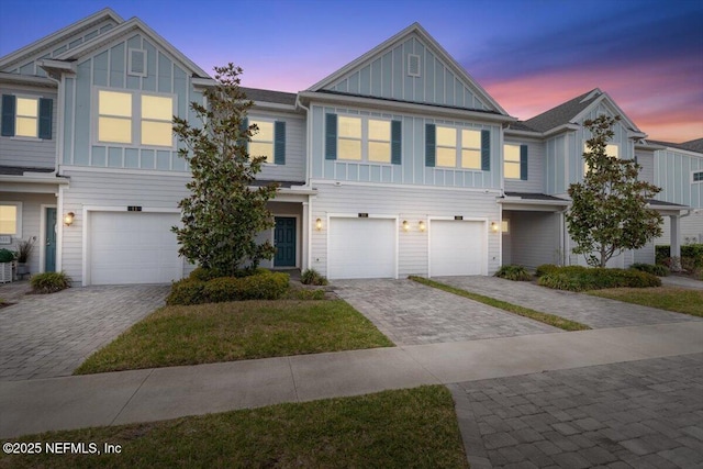 multi unit property with a garage, decorative driveway, and board and batten siding