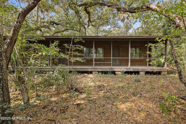 back of house featuring faux log siding and covered porch