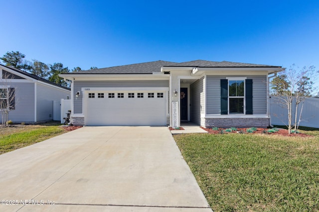 prairie-style home featuring concrete driveway, stone siding, an attached garage, fence, and a front yard