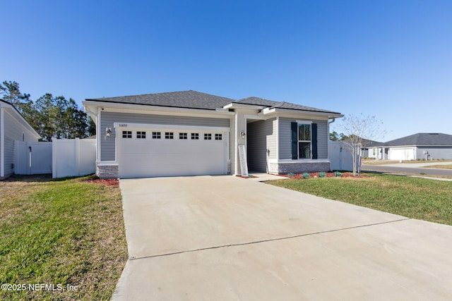 prairie-style home with a garage, fence, concrete driveway, stone siding, and a front lawn