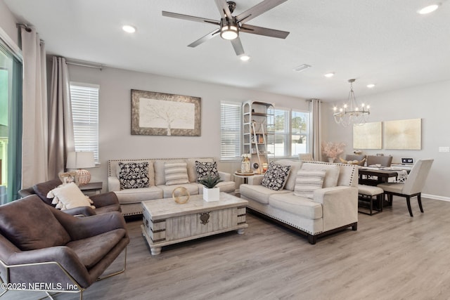 living room featuring ceiling fan with notable chandelier, light wood finished floors, visible vents, and recessed lighting