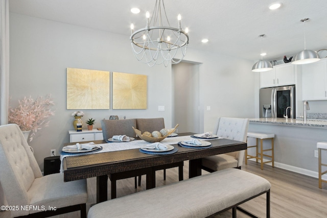 dining room featuring light wood-style floors, baseboards, an inviting chandelier, and recessed lighting