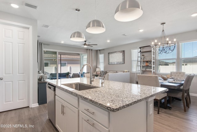 kitchen with light wood-type flooring, open floor plan, a sink, and stainless steel dishwasher