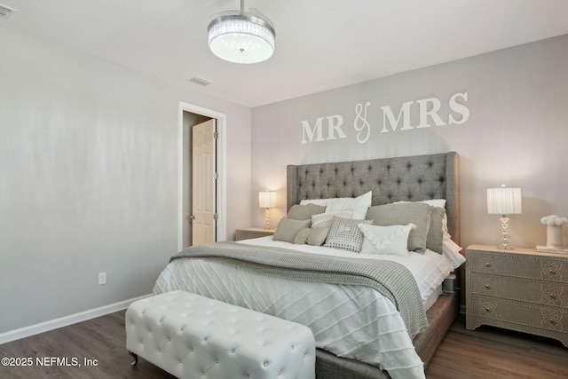 bedroom featuring baseboards, visible vents, and wood finished floors