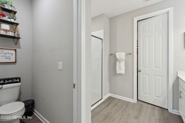 full bath with baseboards, wood finished floors, toilet, and a shower stall