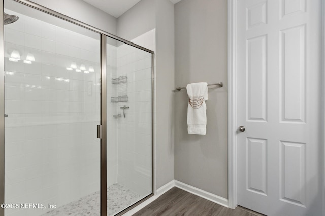 bathroom featuring a stall shower, baseboards, and wood finished floors