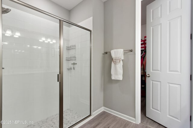 full bath featuring wood finished floors, a shower stall, and baseboards