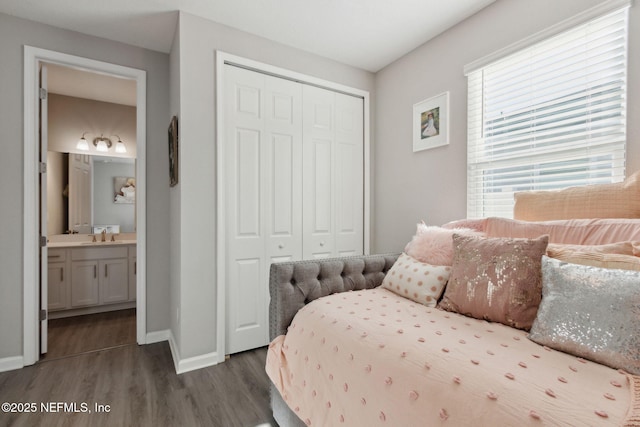 bedroom featuring ensuite bathroom, dark wood-style flooring, a closet, and baseboards