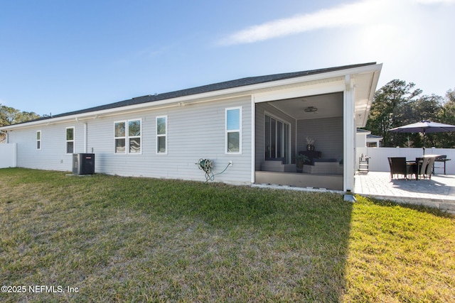 rear view of house featuring a patio, a lawn, a sunroom, central AC, and fence