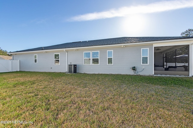 rear view of property with a sunroom, fence, central AC, and a yard